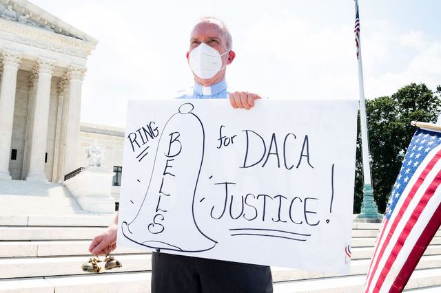 A man wearing a facemask is seen displaying a placard reading " RING BELLS for DACA JUSTICE!" during the demonstration. Pro-DACA (Deferred Action for Childhood Arrivals) demonstration in front of the Supreme Court. The purpose of the rally was to celebrate last month's Supreme Court decision on DACA and to push for a permanent solution.